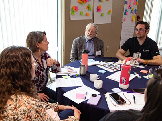 a group of people sitting around a table discussing things