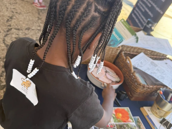 A DMAFB STEAM Village student attendee selecting a sticker prize for her participation in the climate and health spin-the-wheel trivia game.