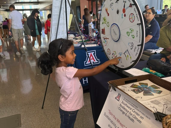 A young girl spinning the climate and health trivia wheel at the SCORCH 'Wellness & Wonder - Connect 2 STEM' table.