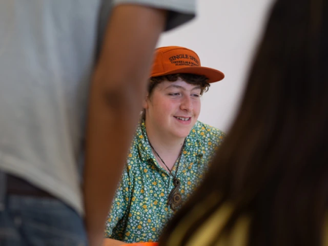 A male youth smiling while presenting his work.