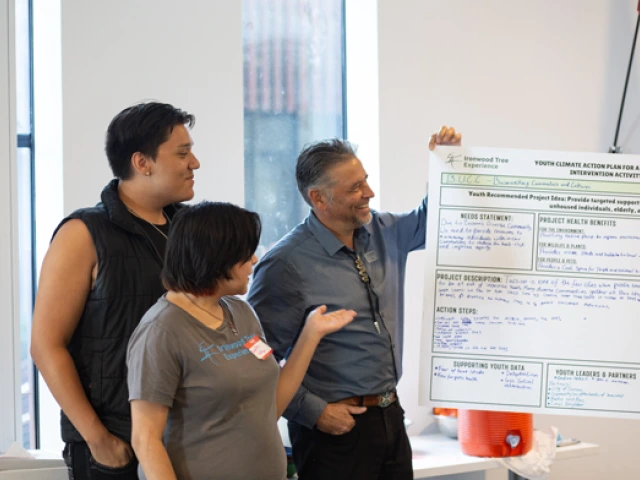 Three individuals admiring a poster illustrating a thought process mapped out at the workshop.