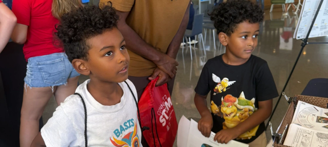 A dad and his two young sons learning about climate and health at the SCORCH 'Wellness & Wonder - Connect 2 STEM' table.