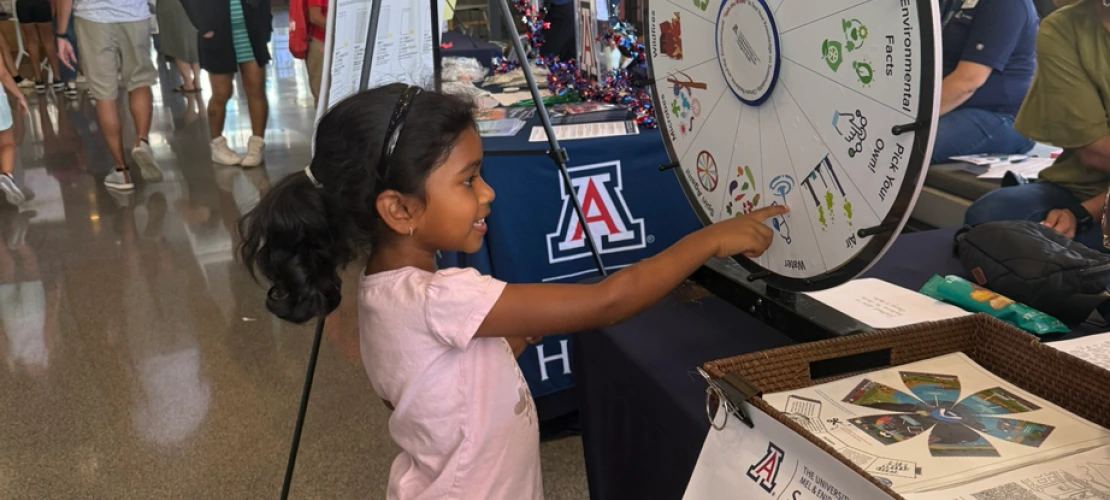 A young girl spinning the climate and health trivia wheel at the SCORCH 'Wellness & Wonder - Connect 2 STEM' table.