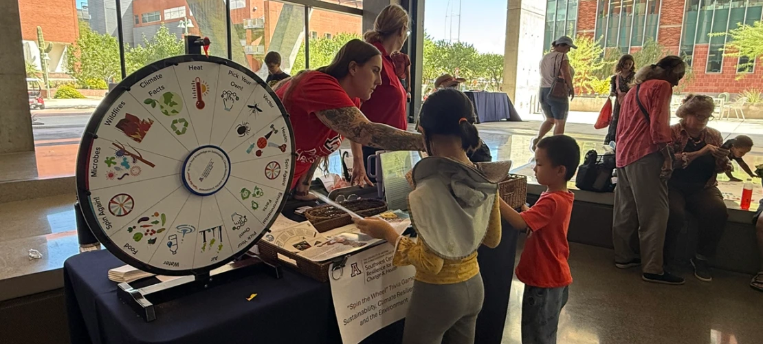 A brother and sister answering climate and health questions posed by MEZCOPH's Des Hartung at the SCORCH 'Wellness & Wonder - Connect 2 STEM' table.