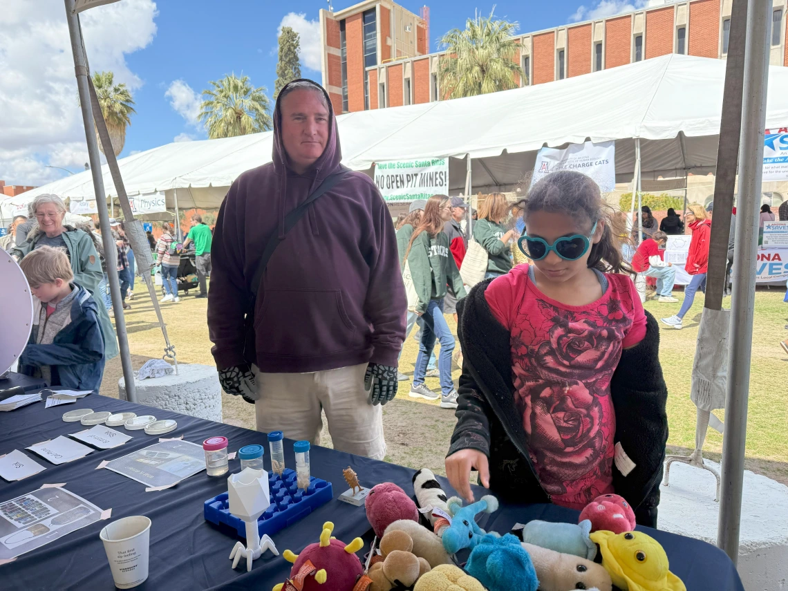 A festival goer learning about germs with giant microbe plushies.