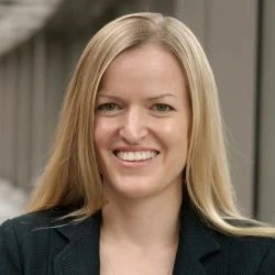 Photograph of Kate Ellingson. She has long blonde hair and is wearing a black colored jacket.