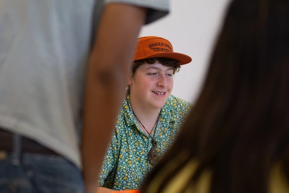 A male youth smiling while presenting his work.