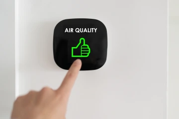 Human pointing to an air quality sensor.