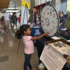 A young girl spinning the climate and health trivia wheel at the SCORCH 'Wellness & Wonder - Connect 2 STEM' table.