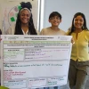 Four young people smiling while holding their poster developed during the workshop.