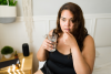 brown haired woman taking a pill holding a glass of water